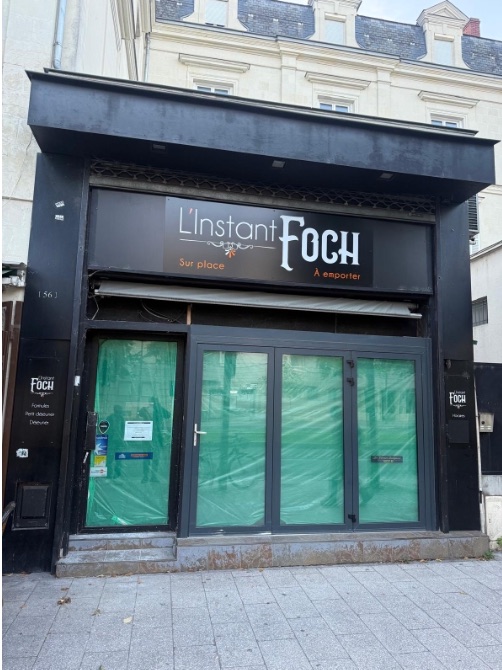 Le local avant travaux, sous l’enseigne L’Instant Foch, vitrines protégées pendant le chantier